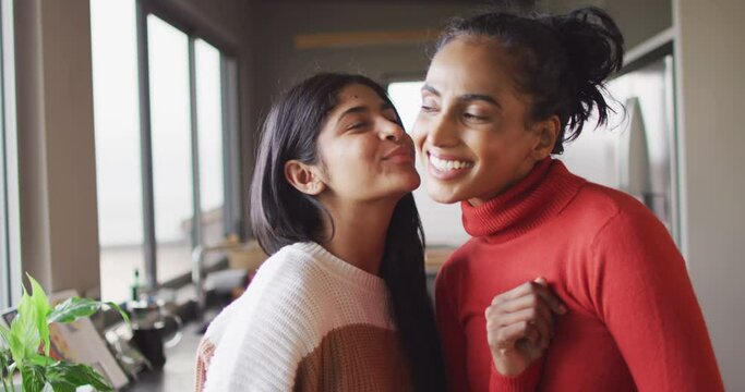 Video of happy biracial female friends kissing on cheek