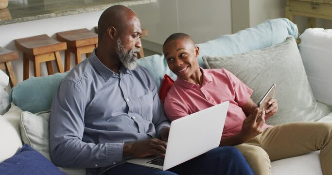 Video of happy african american father and son using laptop together