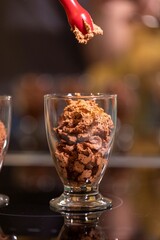 A close up portrait of a nozzle of an espuma bottle just finished spraying sweet and tasty chocolate mousse into a glass cup ready to be served and eaten as a dessert.