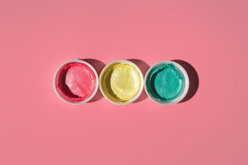 red, yellow and green acrylic paint in open cans on a colored background, top view. traffic light concept