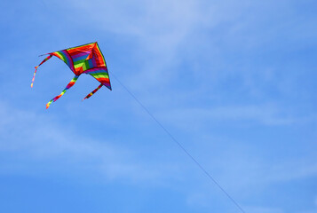 Fototapeta na wymiar kite with many colors that flies high in the blue sky tied to a string