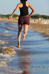 slender athletic young girl running barefoot on the seashore