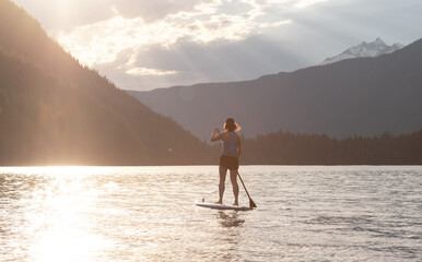 Adventurous Woman Paddle Boarding in a Lake around Canadian Mountain Landscape. Chilliwack Lake,...