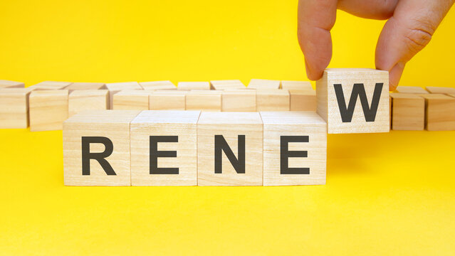 renew symbol. businessman turns wooden cubes the words renew. beautiful yellow background, copy space. business, ecological and renew concept.
