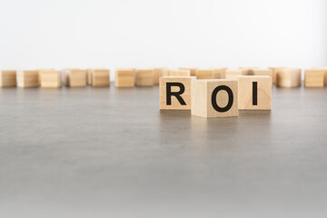 three wooden blocks with letters ROI with focus to the single cube in the foreground in a...