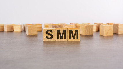 wooden cube with the letter from the SMM word. wooden cubes standing on gray background. SMM - short for Social Media Marketing