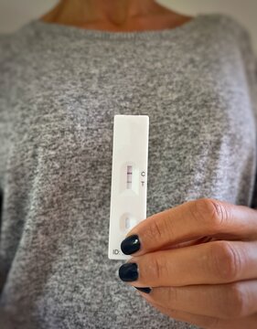 Close-up of a woman holding a positive COVID test