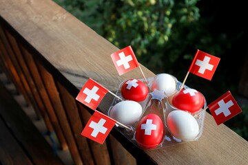 The eggs are painted like the flag of Switzerland: red with white crosses. Next to the eggs are the...