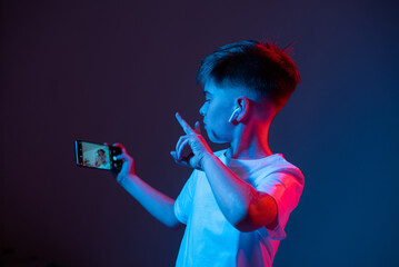 Boy taking selfie on phone neon light