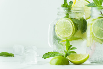 Refreshment mojito cocktail with mint and lime in a glass mug on a white background. Cold summer drink with ice