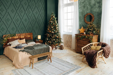 Bedroom decorated for Christmas. Bedroom interior with green walls, double bed and green Christmas tree decorated with emerald and bronze balls and gift boxes on the floor. Christmas interior. Nobody