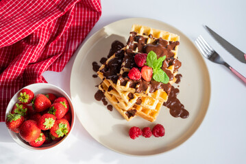 delicious belgian waffles for breakfast with strawberries and raspberries and chocolate