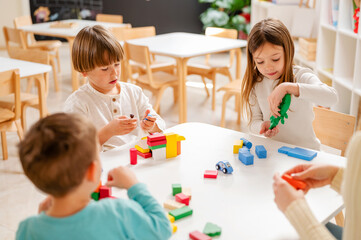 Kindergarten children playing with colorful building blocks. Healthy learning environment. Learning through play.