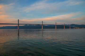 Beautiful modern bridge over the sea on Peljesac in Croatia. In the foreground houses and in the background the Peljesac mountains