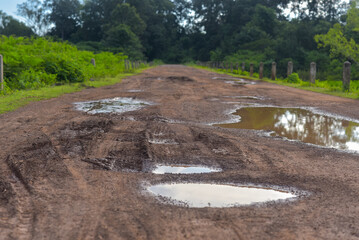 Rural damaged road with muds and holes