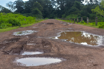Fototapeta premium Rural damaged road with muds and holes
