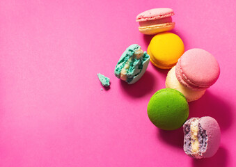 Bright colorful various flavor macarons sweet cookies on high-colored pink background.