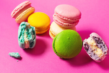 Bright colorful various flavor macarons sweet cookies on high-colored pink background