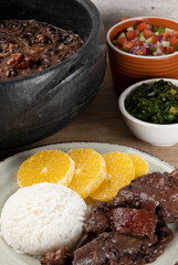 Brazilian traditional food feijoada on green plate.