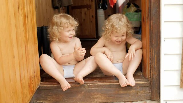 Overjoyed baby twins curly blonde sister talking friendship playing together at countryside house