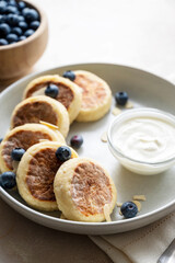Cottage cheese fritters, ricotta pancakes with sour creamand bleberries. Healthy food. Warm background