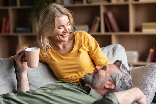 Cheerful Middle Aged Couple Resting Together At Home, Drinking Coffee And Chatting
