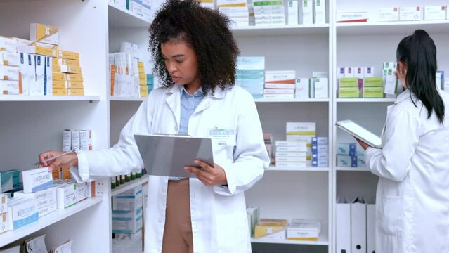 Two pharmacists doing inventory with a clipboard and digital tablet in a pharmacy. Colleagues working together while counting and recording the quantity of medication and stock in a drugstore