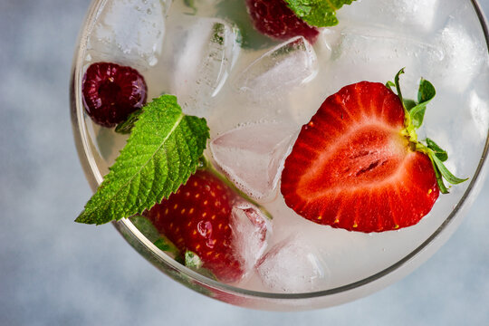 Overhead view of a summer cocktail with fresh raspberries and strawberries in a champagne coupe