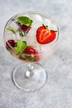 Summer cocktail with fresh raspberries and strawberries in a champagne coupe
