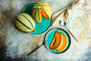 Overhead view of cantaloupe melons, slices of melon and a glass of white wine