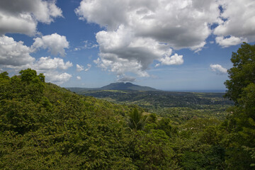Blue sky with clouds over the mountains, green summer forest in Caribbean island