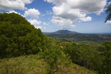 Fototapeta na wymiar Blue sky with clouds over the mountains, green summer forest in Caribbean island