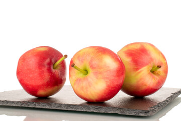 Three ripe sweet red apples on a slate stone, close-up, isolated on a white background.