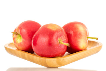 Several ripe sweet red apples with a wooden saucer, close-up isolated on a white background.