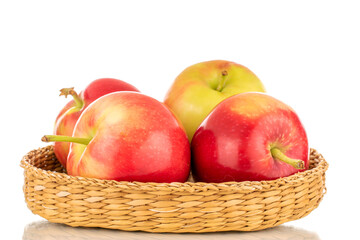 Several ripe sweet red apples in a straw plate, close-up isolated on a white background.
