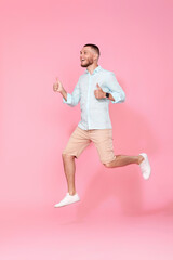 man in summer clothes jumping on pink background.