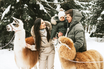 family of three young beautiful woman and man fashion stylish winter clothes overall, baby boy son...