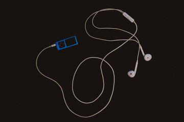 vintage music player on a black surface with white wired earphones