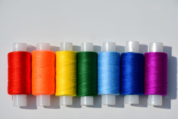 Spools of sewing thread of seven colors of the rainbow close-up on a light background