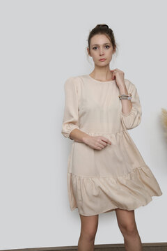 Serie of studio photos of young female model in casual beige midi dress
