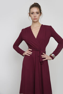 Serie of studio photos of young female model in burgundy wrap dress. 