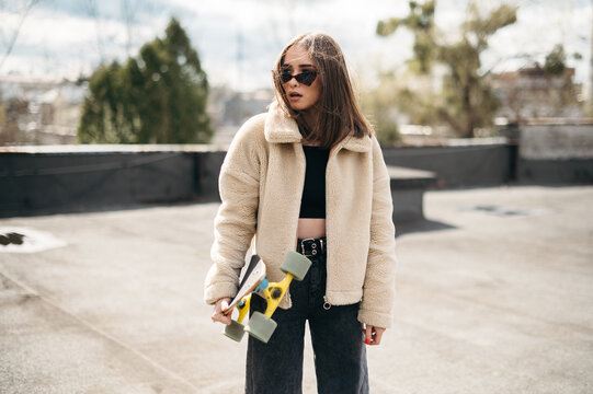Siriusly woman standing on roof with skateboard in hands