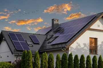Modern house with blue solar panels on the roof. End of the day, sunset. Idyllic atmosphere. - obrazy, fototapety, plakaty