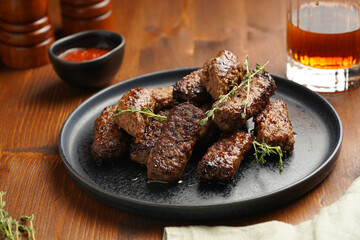 Traditional south european skinless sausages cevapcici made of ground meat and spices on black plate on dark wooden board, with thyme