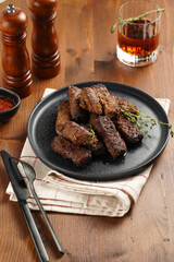 Traditional south european skinless sausages cevapcici made of ground meat and spices on black plate on kitchen towel with thyme