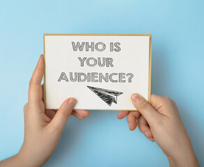 Person holds card with words Who is your Audience on blue