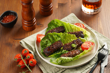 Traditional south european skinless sausages cevapcici made of ground meat and spices on lettuce...
