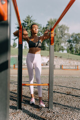 Portrait of young African fit slim woman on sports ground at bright sunny day