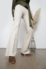 Serie of studio photos of young female model wearing green silk blouse and basic beige flared trousers