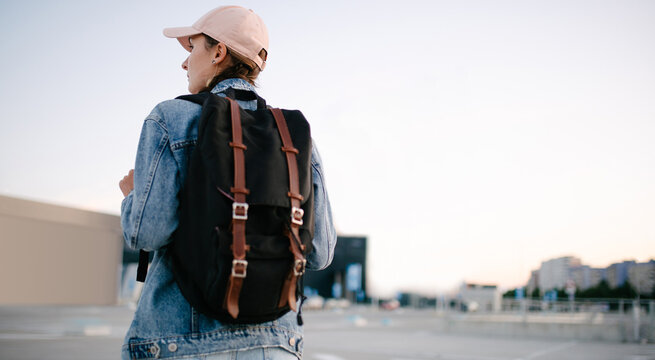 Tourist girl with her backpack looking at city landscape, back view Adventure and travel in the concept . Backpack rear view. Tourism in city.